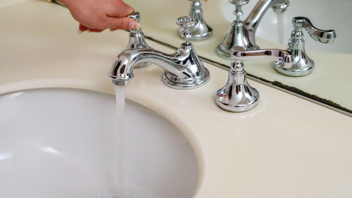 Chrome faucet with water flowing into a sink