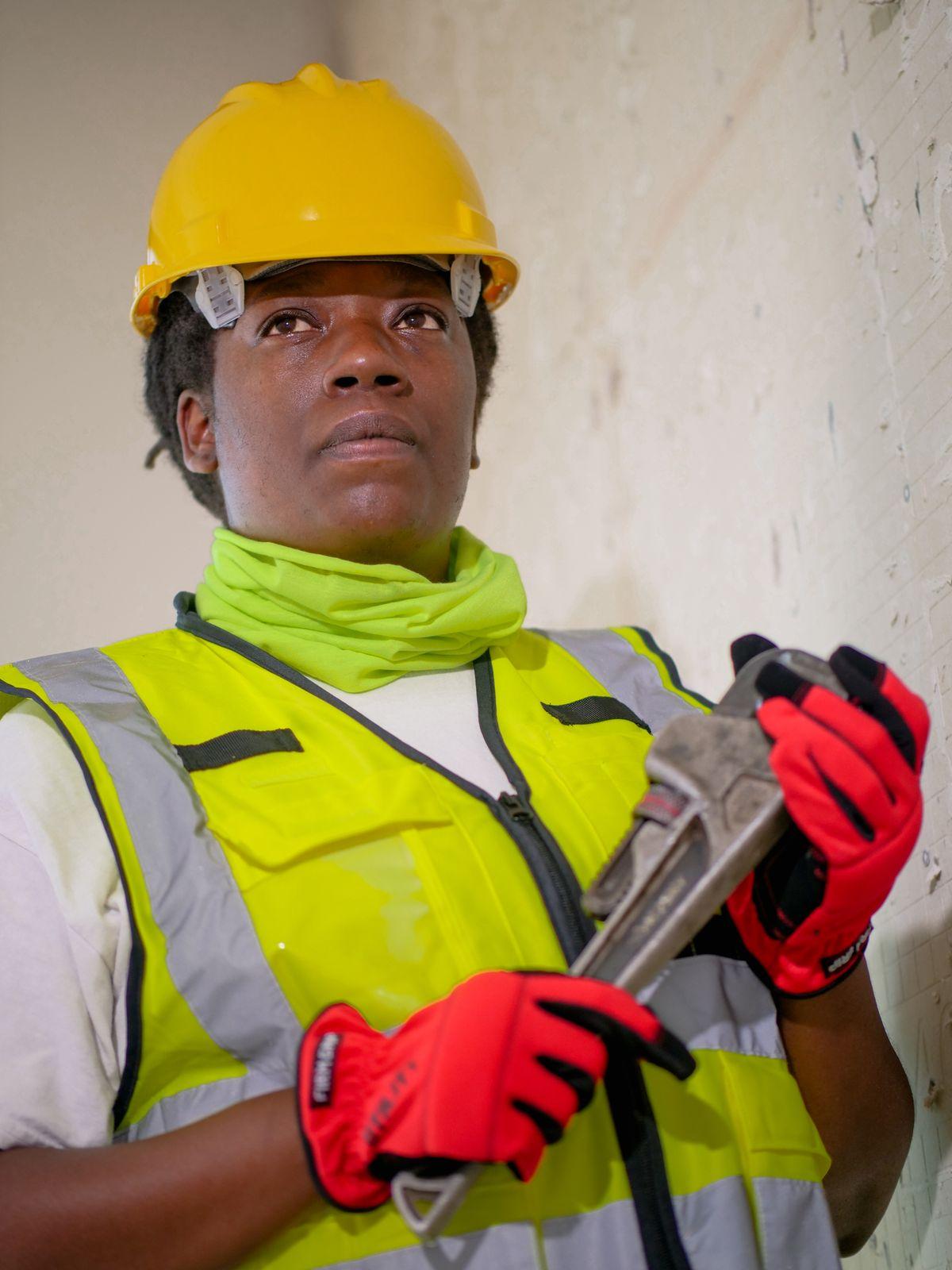Plumber in safety gear holding a pipe wrench